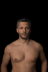 Fototapeta premium A man with a shaved chest stands in front of a black background
