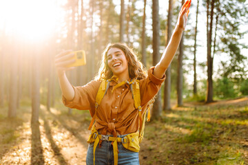 Happy woman tourist taking picture of herself while walking in a sunny forest.  find the route....
