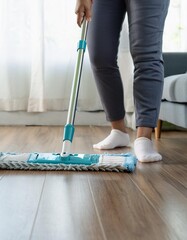 Housekeeper mopping the laminate wooden floor and cleaning dust during chores daily routine.