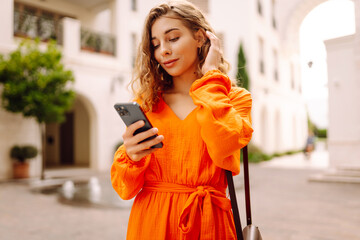 Young woman tourist walking on city street using smartphone mobile phone. Communication with friends.Blogging.