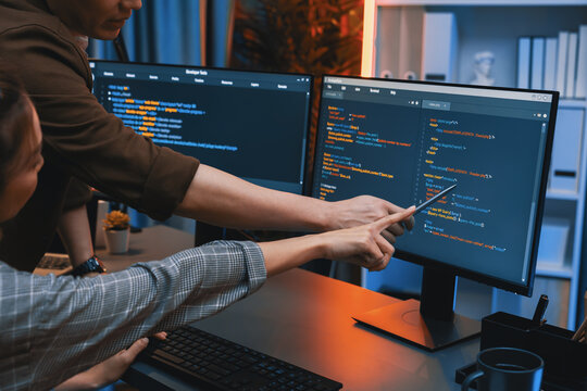 IT developers discussing with point to intelligent website development coder system running data online two screens information technology at neon light room at modern office. Infobahn.