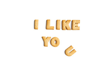 The phrase I like you, made up of cookie letters on a white background. Interesting spelling with crackers