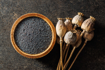 Dry poppy seed and poppy head on black table. Top view.