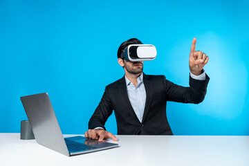 Skilled business man looking at data analysis while sitting at table with laptop and wearing VR glasses. Project manager working by using virtual reality system or connecting at metaverse. Deviation.