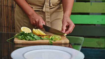 Close-up of hands preparing fresh ingredients for a delicious fish barbecue with lemon and herbs on a wooden cutting board outdoors
