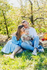 Fototapeta premium Father and mother holding little son in nature, concept of beautiful family bonds. Family portrait of parents with a little son. The concept of a happy family