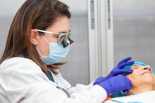 Dermatologist carrying out a skin biopsy on the face of a senior adult patient
