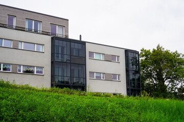 Grey building with many windows. Green grass hill in the front. Summer daytime. Tree foliage on the right. Tallinn, Estonia, Europe. July 2024