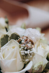 Close-up of wedding rings on a white rose bouquet, symbolizing love and commitment
