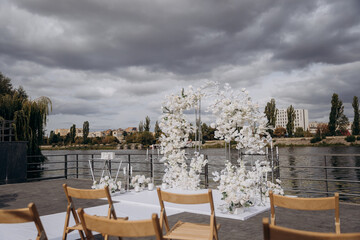 Elegant outdoor wedding ceremony setup with white floral arrangements by the water