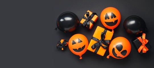 Funny Halloween balloons and gift boxes on black background with space for text, top view