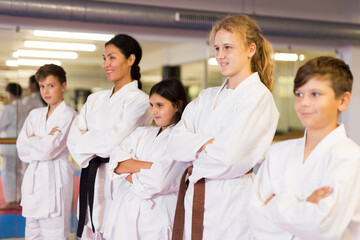 Fototapeta premium Portrait of teenager children with their female instructor posing at gym after group training