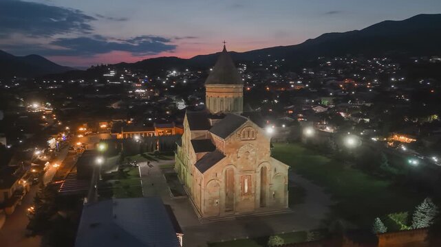 Night aerial shot of Svetitskhoveli Cathedral in Mtskheta, Georgia - sunset sky at background