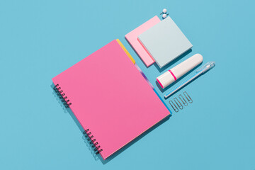 Notebook, highlighter, pen, push pins and paper sheets on blue background. Office and school...