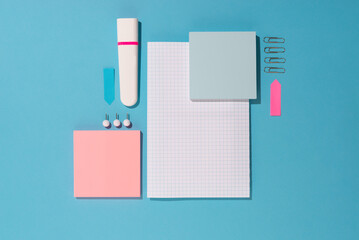 Highlighter, pen, push pins and paper sheets on blue background. Office and school supplies on blue...