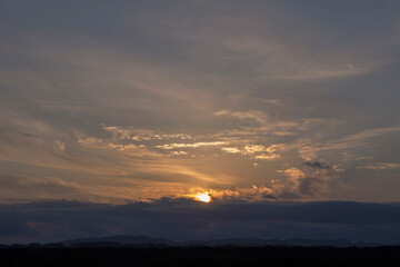 Fototapeta premium Sunset sky and the sun setting in thin clouds