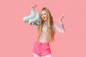 Beautiful young happy woman with vintage roller skates on pink background