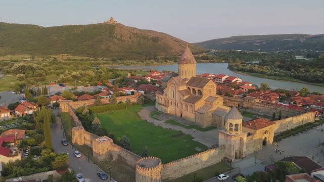 Aerial around view of great Svetitskhoveli Cathedral in Mtskheta, Georgia. Old Svetitskhoveli Church in center of Mtskheta village - UNESCO World Heritage. Jvari monastery on the mountain