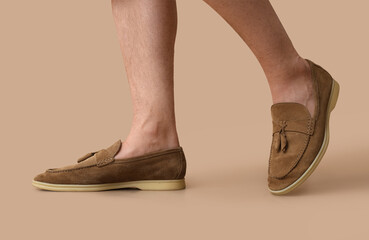 Legs of young man in stylish shoes on brown background
