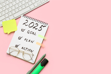 Notebook with to do list, sticky notes and computer keyboard on pink background. New year goals concept