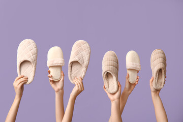 Female hands holding different slippers on lilac background
