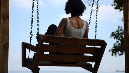 Happy woman ride on swing at tropical at sea beach. Carefree lady enjoying rest near ocean. Adult...