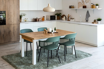 Interior of light kitchen with dining table and white counters