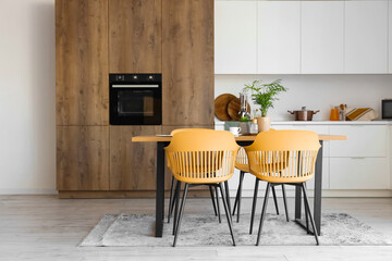 Interior of light kitchen with dining table and white counters