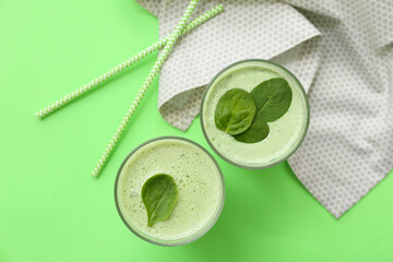 Glasses of fresh spinach smoothie on green background