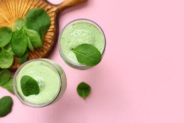 Glasses of fresh spinach smoothie on pink background