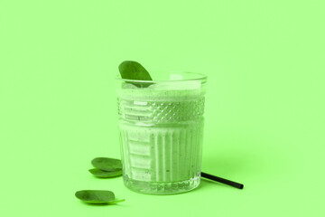 Glass of fresh spinach smoothie on green background