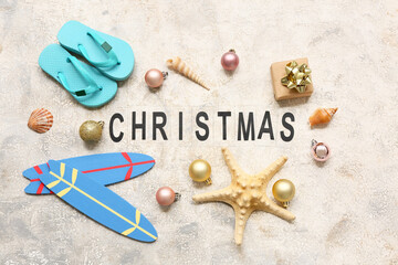 Starfish, flip-flops, toy surfboard and Christmas decor on grey grunge background. Top view