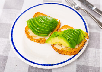 Toast with fresh avocado and cheese served as snack on platter