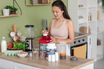 Sporty young happy Asian woman making protein shake at home