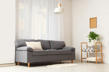 Cozy sofa with cushion and shelving unit in interior of living room