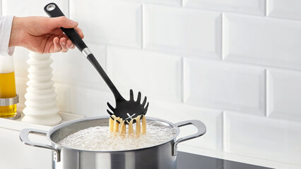 Closeup of a person steering a cooking pot of pasta. © Carterson