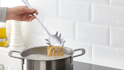 Closeup of a person steering a cooking pot of pasta. © Carterson