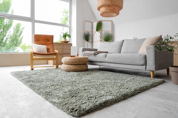 Cozy sofa, armchair and wicker pouf with decor in living room