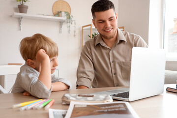 Cute boy with his father doing homework at home