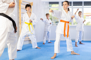 Fototapeta premium Children in kimono standing in fight stance during group karate training