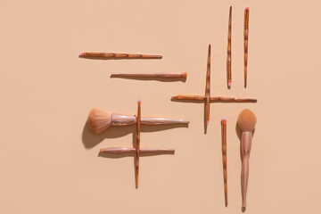 Different stylish makeup brushes on beige background