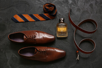 Set of male accessories with shoes, perfume, belt and tie on black background. Top view