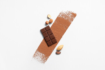 Composition with tasty chocolate, cocoa powder and nuts on light background