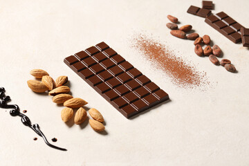 Sweet chocolate with almond nuts, cocoa beans and powder on white background