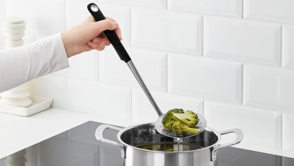 Closeup of a person steering veggeis in a cooking pot.