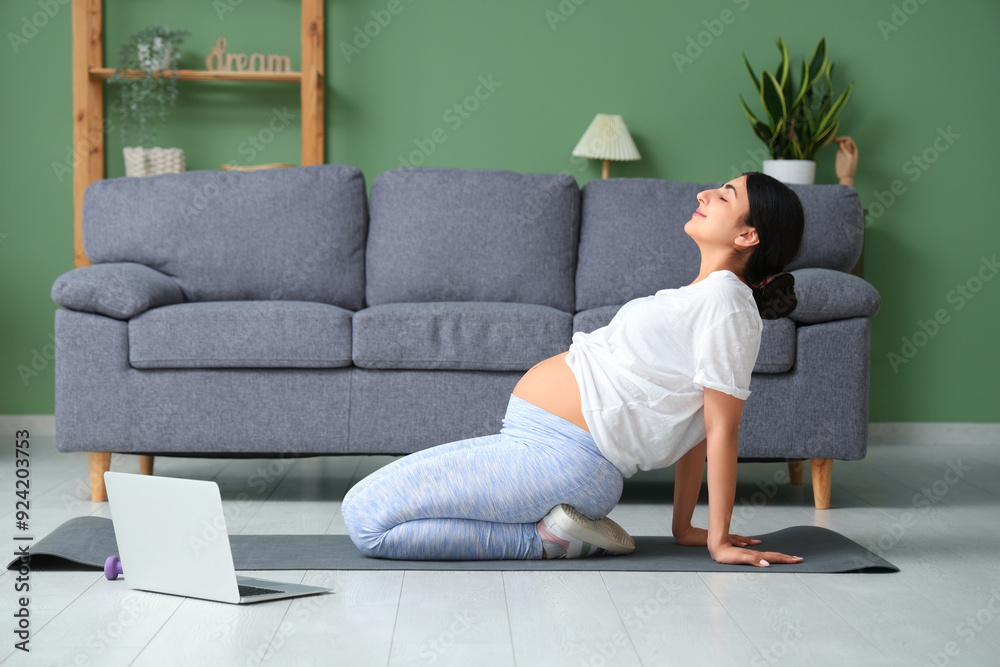 Sticker beautiful young pregnant woman doing yoga in living room