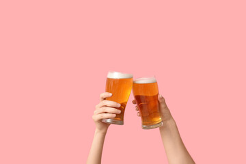 Female hands with fresh beer in pints on pink background