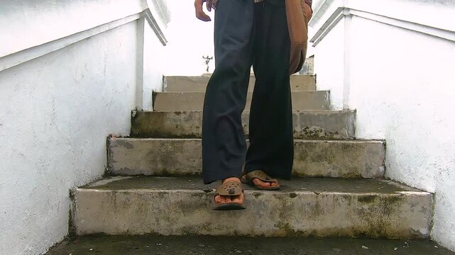 Close up feet of young man walking down the stairs with bag. Attractive male tourist traveler travel alone on street.