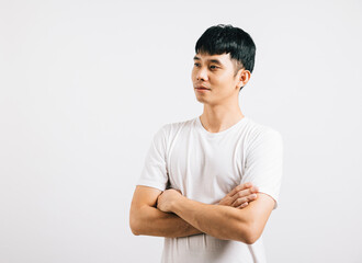 Smiling Asian man showcases confidence with crossed arms, epitomizing success. Studio portrait isolated on white, conveying a friendly and positive demeanor.