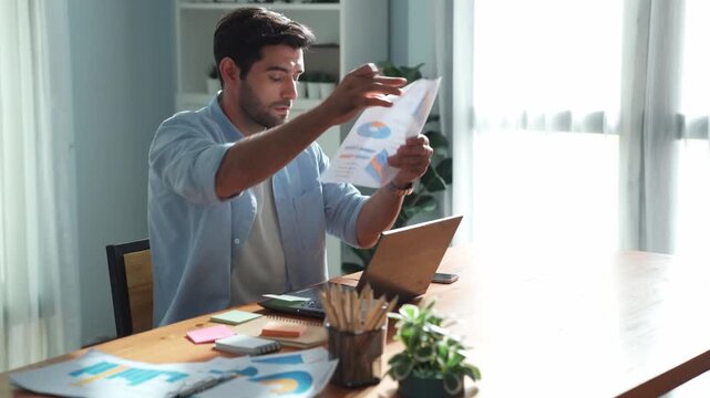 Professional smart manager working on laptop while looking at data analysis. Leader compare financial statistic graph while making decision at meeting table with document scatter around. Convocation.